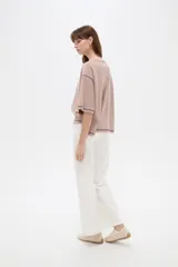 Remera de algodón color crudo, con cuello redondo a la base, mangas 3/4 holgadas y costuras con pespuntes en tono contrastante.