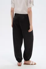 Pantalón de poliéster color negro, de tiro alto y corte holgado con frunces en los tobillos.