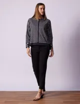 Blusa de gasa estampada con líneas verticales negras sobre fondo beige, de manga larga con puño abotonado. Espalda con abertura y botón.