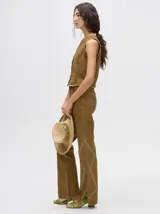 Pantalón de denim color marrón, de tiro alto y calce ochentoso con terminación estilo oxford. Cuenta con apliques metálicos decorativos alrededor de los bolsillos y a lo largo de las costuras exteriores.