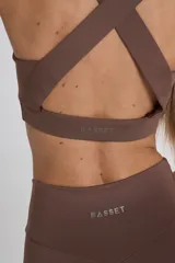 Top deportivo marrón con breteles anchos cruzados en la espalda y banda elástica inferior.