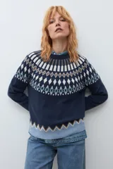Sweater de punto en color azul marino con diseño jacquard geométrico en tonos blanco, marrón y verde en el canesú, puños y ruedo. Presenta cuello redondo y mangas largas.