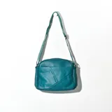 Bandolera verde petróleo de cuero sintético con correa de tela estampada.