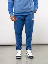 Pantalón deportivo de piqué color azul, con franjas laterales en contraste, escudo del Club Nacional de Football y detalle con la fecha de fundación.