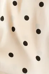 Vestido corto de crepé de satén color beige con estampado de lunares negros, escote drapeado halter con tiras para anudar al cuello y fruncidos laterales.