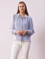 Camisa celeste de gasa, marca Tahari. Cuello con solapa y abertura central con botones ocultos. Manga larga abullonada con puño y botones. Forro de gasa a tono.