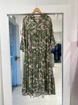 Vestido midi verde con estampado botánico en tonos beige, escote en V con cuello mao y cierre frontal de botones, de manga larga y diseño en capas.