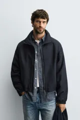 Cazadora de corte cropped confeccionada en tejido de algodón con ligero acolchado interior. Presenta cuello subido, cierre frontal con cremallera, mangas largas con puños elásticos y bolsillos laterales de vivo.