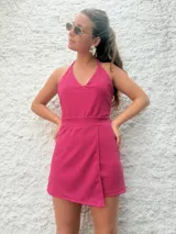 Mono corto fucsia con escote halter y falda cruzada.