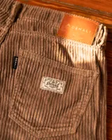 Pantalón de corte clásico confeccionado en pana gruesa color beige, con diseño de cinco bolsillos y textura acanalada.