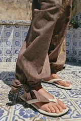 Sandalias planas tipo ojota de color beige, con tira delantera acolchada con separación para el dedo y suela fina.