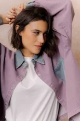 Camisa lila de calce relajado y manga larga, con cuello clásico, puños y bolsillo delantero en denim contrastante. Cierre frontal con broches metálicos.