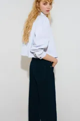 Jean de tiro alto y pierna ancha en denim de algodón negro, con diseño clásico de cinco bolsillos, cierre de cremallera y botón metálico.