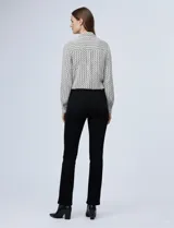 Camisa de manga larga, color blanco y negro, con cuello con solapa y abertura central con botones ocultos. Presenta un estampado geométrico repetitivo.