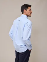 Camisa de manga larga para hombre, confeccionada en algodón con efecto peach (textura suave). Presenta un estampado de cuadros vichy en tonos azul marino y blanco, cuello con botones y un bolsillo de parche en el pecho izquierdo.