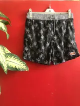Short de baño negro con estampado de palmeras blancas, cintura elastizada a rayas blancas y negras, cordón ajustable y logo de Reef en el lateral.