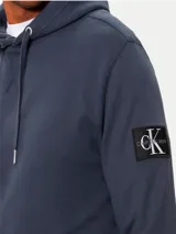 Buzo con capucha Calvin Klein color azul petróleo, con bolsillo tipo canguro, cordones ajustables y logo de la marca en la manga. Confeccionado en felpa de algodón.