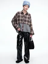 Camisa de corte relajado con diseño combinado. La parte superior presenta un estampado a cuadros en tonos marrones y negros, mientras que la parte inferior destaca por un panel de rayas verticales en color bordó. Cuenta con cierre frontal de botones y mangas largas.