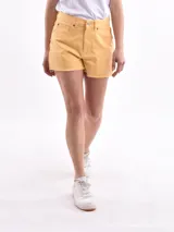 Short de jean color amarillo, de tiro medio con cierre y botón frontal, bolsillos laterales y traseros, y ruedo deshilachado.