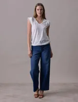 Remera blanca de modal, marca French Laundry, con escote en V. Presenta apliques de puntilla en las mangas y el escote, y un detalle fruncido en los hombros.