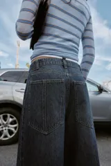 Jeans de tiro alto con corte balloon y pernera holgada. Presenta diseño de cinco bolsillos, cierre frontal con cremallera y botón, y detalle de costuras marcadas en el delantero y la espalda.