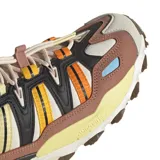 Championes adidas modelo Hyperturf Adventure, con diseño técnico inspirado en el outdoor. Presenta una combinación de colores tierra, negro y detalles en naranja y celeste, con entresuela con tecnología Adiprene+ y suela de gran agarre.