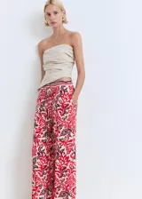 Pantalón largo de corte recto y tejido fluido, con estampado paisley en tonos rojo, bordó y crudo. Cuenta con cintura elástica con cordón ajustable y bolsillos laterales.