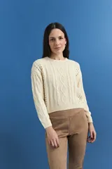 Sweater de tejido de punto color crema, con diseño de ochos y detalles calados. Presenta escote redondo a la base, mangas largas y corte recto.