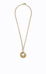 Collar largo de metal dorado con cadena de eslabones medianos y un colgante redondo compuesto por anillos repujados superpuestos con detalle central calado.