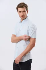 Camisa de manga corta de algodón en color celeste con microdiseño geométrico a cuadros, cuello camisero y bolsillo frontal con logo bordado.