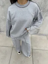 Buzo oversize de color gris, con diseño de costuras expuestas en contraste y terminaciones desflecadas en mangas y ruedo.