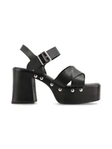 Sandalia de plataforma color negro, con taco ancho, tiras cruzadas en el empeine y tira al tobillo con hebilla ajustable. Cuenta con detalles de tachas metálicas en los laterales de la plataforma y el talón.
