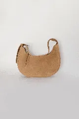 Bolso de hombro tipo banana, color camel/marrón claro, confeccionado en cuero metalizado. Presenta costuras decorativas en el borde superior y cierre con tirador de cuero. Incluye asa corta de cuero y correa larga desmontable de cadena metálica.