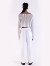 Sweater crop negro de punto abierto y manga larga con brillo sutil. Presenta escote bote y diseño relajado.
