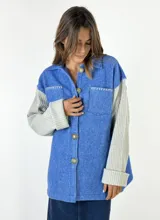 Chaqueta azul con diseño de espiga, mangas largas de punto gris y cierre frontal con botones.