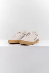 Zapatillas deportivas de cuero color blanco hueso con detalles bordados y suela color caramelo.