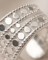 Anillo ancho de acero quirúrgico compuesto por múltiples bandas texturizadas con perforaciones circulares y detalles de brillo.