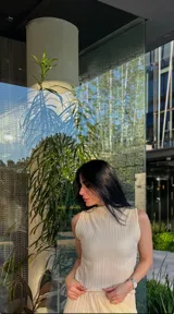 Musculosa sin mangas color beige claro, con cuello alto y textura plisada vertical.