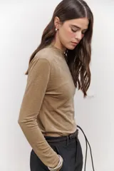 Polera de terciopelo color dorado, con cuello alto y mangas largas.