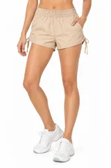 Short de poliamida color beige, holgado, de tiro medio con cintura elástica y detalles de frunces con cordones ajustables en los laterales.
