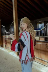 Sweater tejido en hilado 100% algodón con diseño a rayas verticales en tonos rojo, blanco, marrón y negro. Presenta flecos en el ruedo y bordados en el escote.