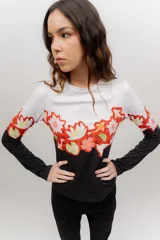 Remera de manga larga de algodón elastizado, con cuello redondo y estampado geométrico floral en tonos blanco, amarillo, verde y rosado.