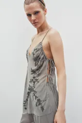 Top de tul con escote en pico y tirantes finos. Presenta bordados florales con aplicación de lentejuelas y laterales ajustables mediante lazadas.