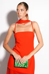 Vestido largo negro confeccionado en crepé y gasa, de corte al cuerpo con escote recto, tiritas finas y falda larga semitransparente con tajo lateral pronunciado. Incluye accesorio tipo corbatín a juego.