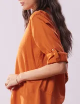 Camisa color beige de tencel, marca Hester & Orchand, con cuello con solapa, escote en V, abertura central con botones y bolsillos delanteros. Las mangas son largas y regulables con presilla y botón.