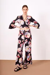 Pantalón negro con estampado floral multicolor, de corte acampanado y cintura elástica con cordón ajustable.