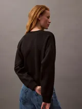 Buzo negro de cuello redondo, confeccionado en tejido fleece de mezcla de algodón y poliéster. Presenta el logo de archivo de Calvin Klein bordado en blanco en el frontal.