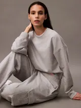 Pantalón de chándal gris de corte holgado con bolsillos cargo laterales, cintura elástica con cordón y bajos elásticos. Confeccionado en felpa de mezcla de algodón.