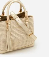Cartera satchel mediana color dorado, con textura de paja, correa de mano, asa larga desmontable y detalle de tassel.