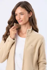Campera polar de cuello alto con cierre frontal completo, diseñada en un tono beige suave. Presenta un corte entallado y ligero, ideal para uso diario o como prenda de abrigo versátil.